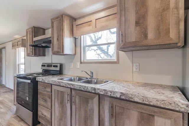 a kitchen with granite countertop a stove top oven and cabinets