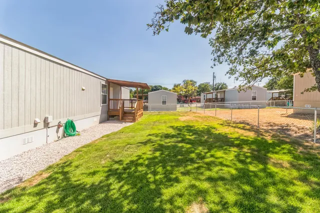 a view of a backyard with wooden fence and a bench