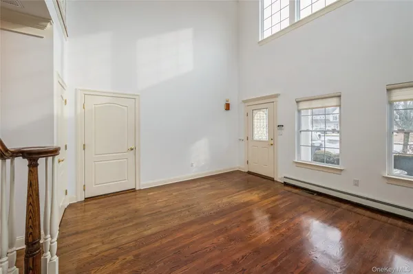 an empty room with wooden floor cabinet and windows