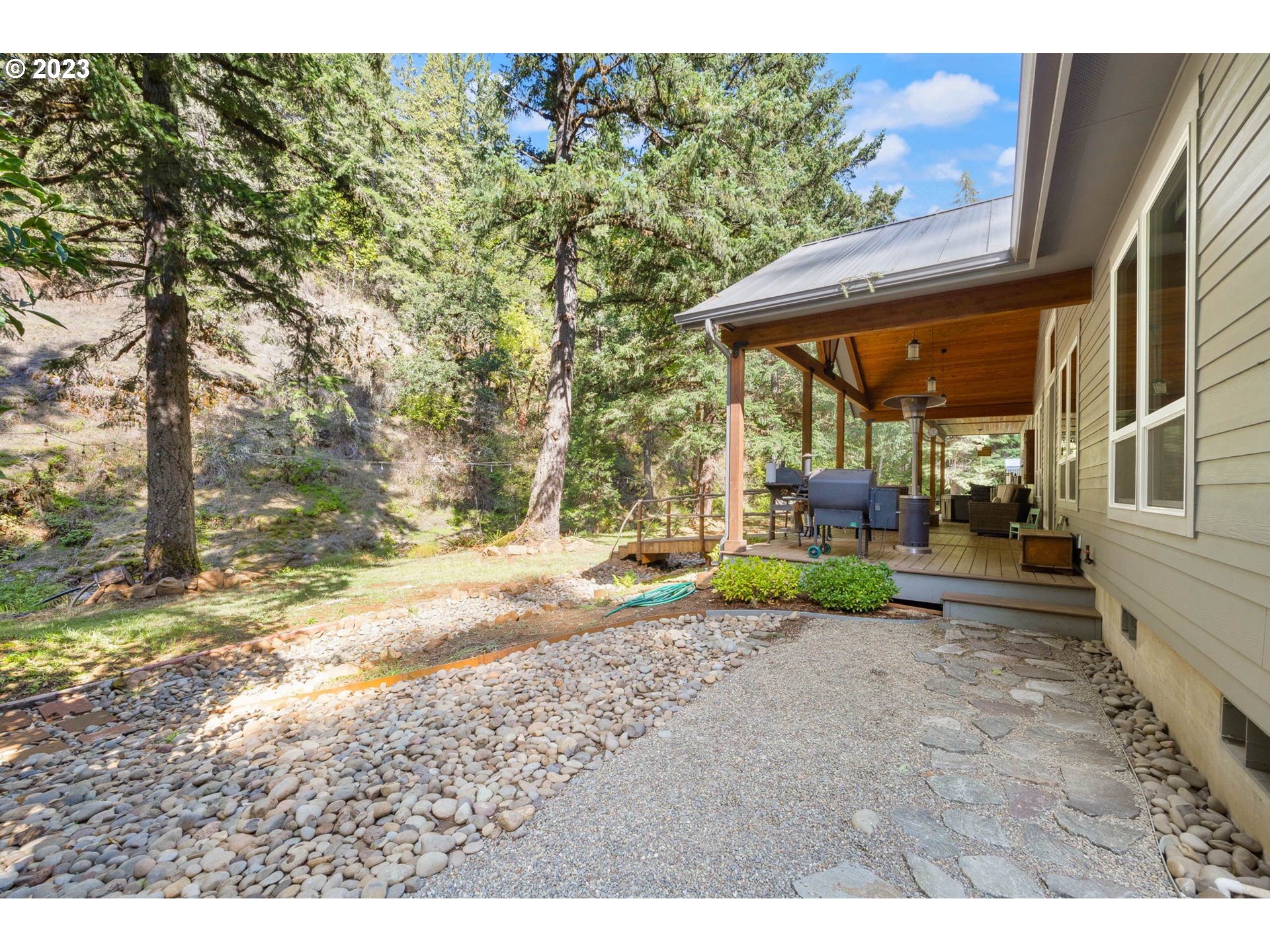 37693 Hills Creek Road Springfield, OR 97478 - Photo 34 of 48 a view of a patio with table and chairs under an umbrella with large trees