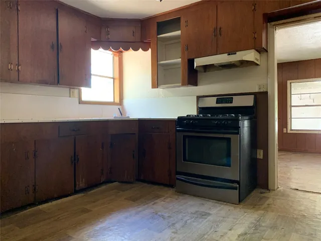 a kitchen with granite countertop wood cabinets stainless steel appliances and a window