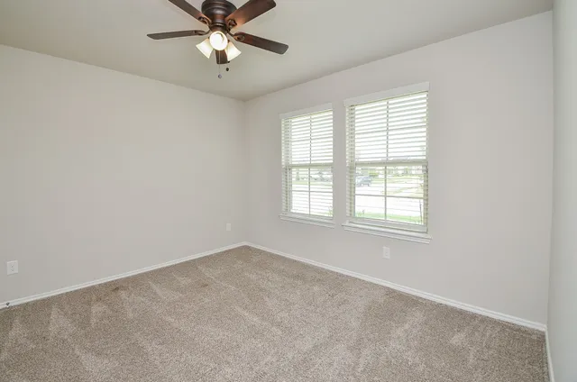 an empty room with a window and a fan