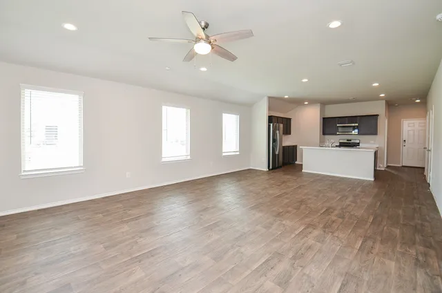 a view of an empty room with a window and kitchen view