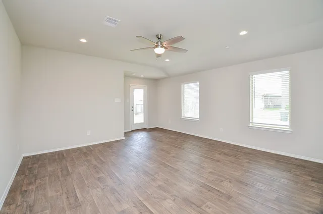 a view of an empty room with wooden floor and a window