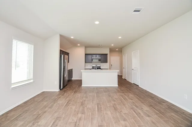 a view of kitchen with kitchen island a sink wooden floor and a refrigerator