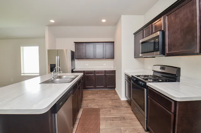 a kitchen with stainless steel appliances granite countertop a sink stove microwave and refrigerator
