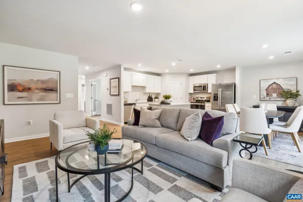 a living room with furniture kitchen view and wood floor