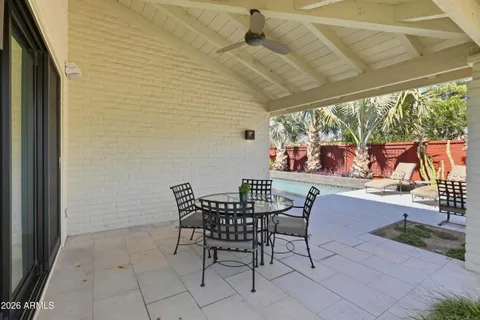 a patio with table and chairs and potted plants