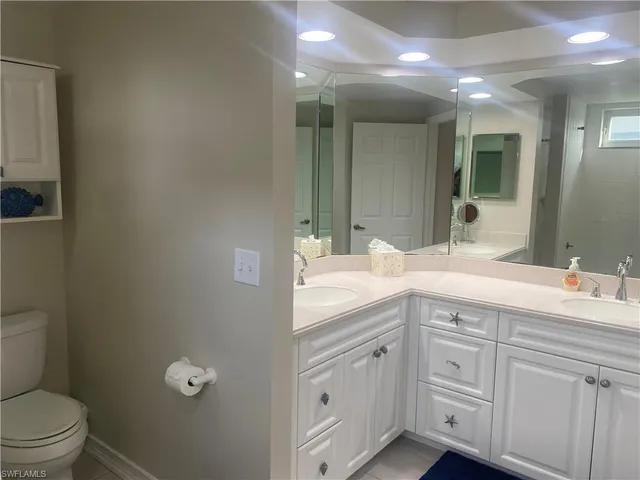 a spacious bathroom with a granite countertop sink a toilet and a mirror