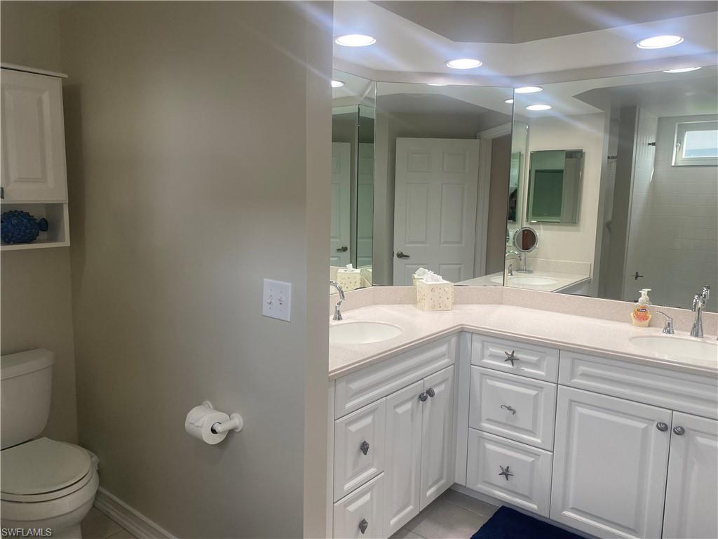 295 Waterside Circle, Unit 1102 Marco Island, FL 34145 - Photo 19 of 31 a spacious bathroom with a granite countertop sink a toilet and a mirror