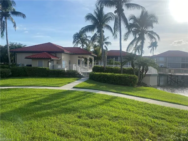 a view of a house with a big yard and palm trees