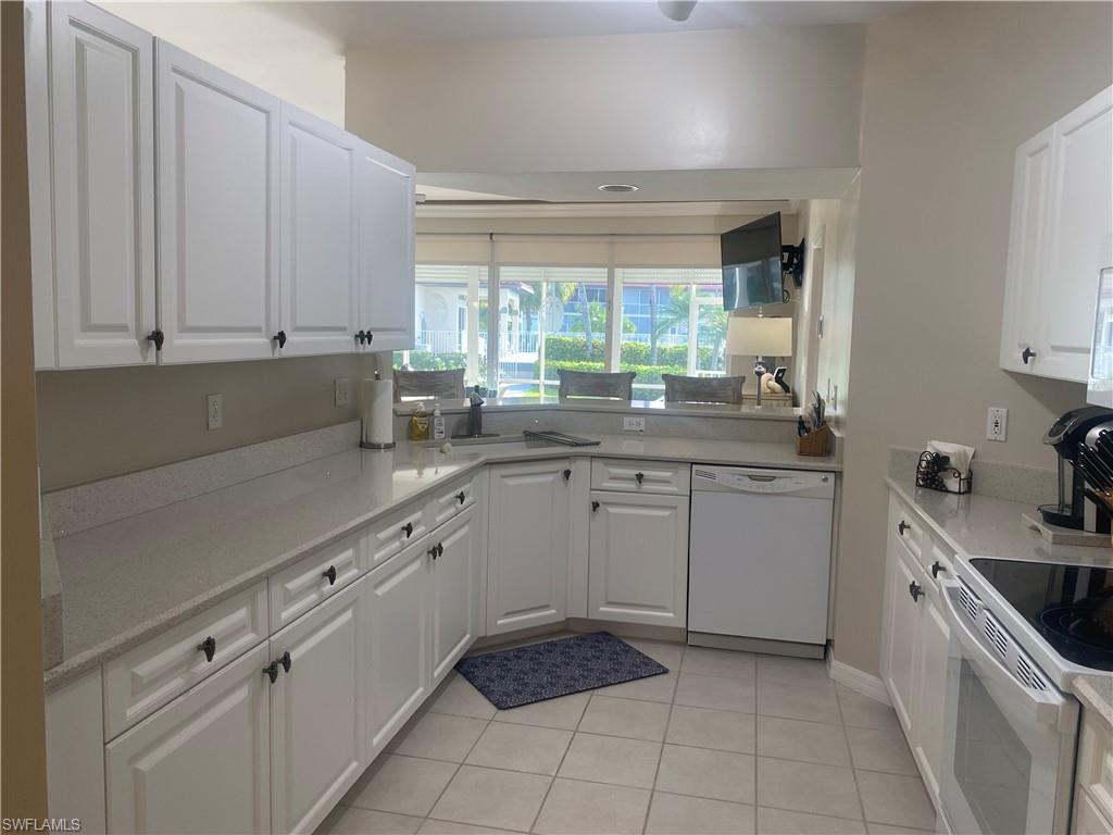 295 Waterside Circle, Unit 1102 Marco Island, FL 34145 - Photo 5 of 31 a kitchen with a sink window and cabinets