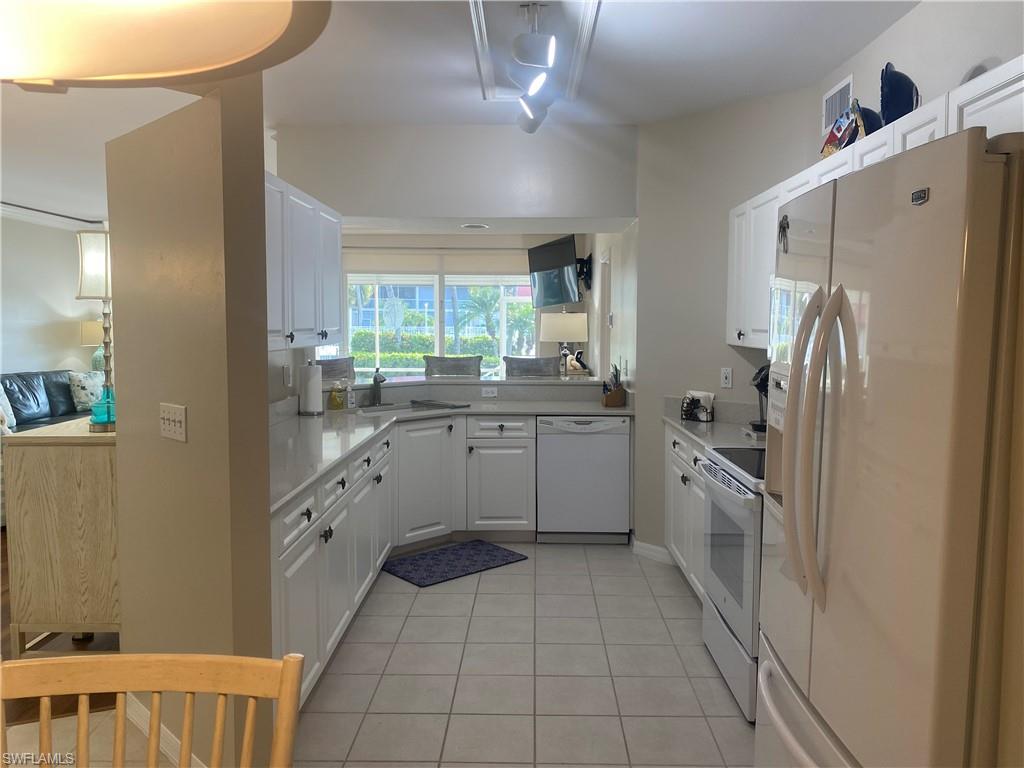 295 Waterside Circle, Unit 1102 Marco Island, FL 34145 - Photo 7 of 31 a kitchen with a refrigerator sink and cabinets