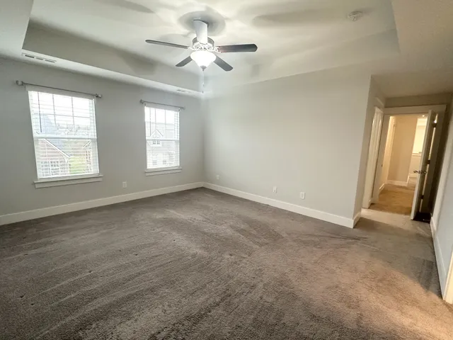 an empty room with chandelier fan and windows