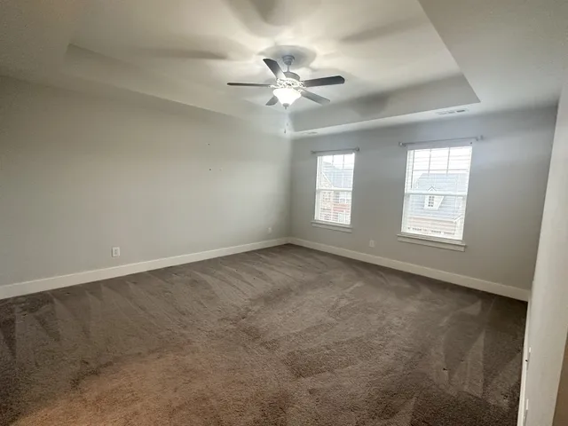 an empty room with windows and fan