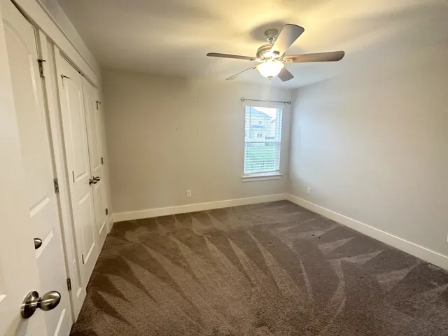 an empty room with windows and fan
