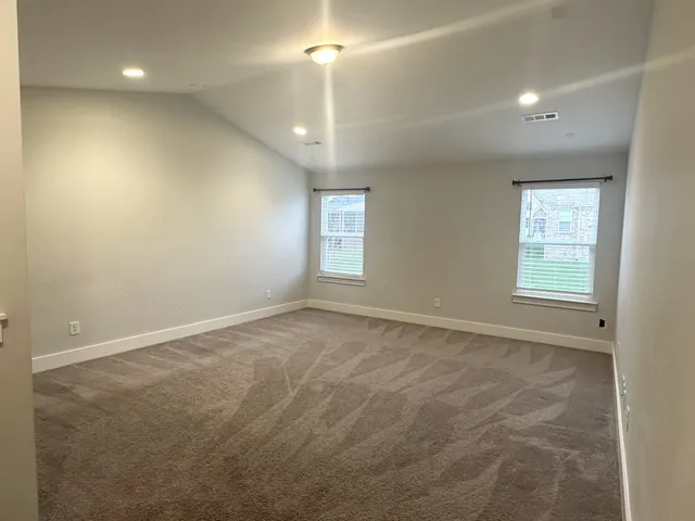 an empty room with windows and ceiling fan