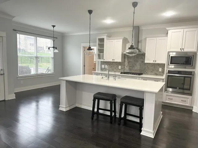 a kitchen with stainless steel appliances granite countertop a sink a stove and a wooden floors