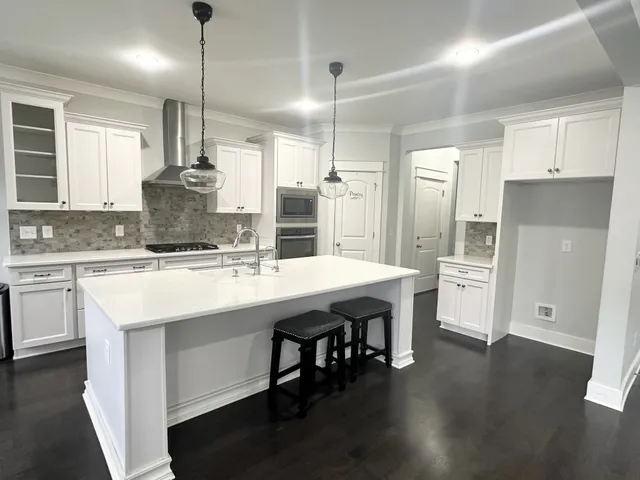 a kitchen with stainless steel appliances granite countertop a sink a stove a refrigerator and island with wooden floor