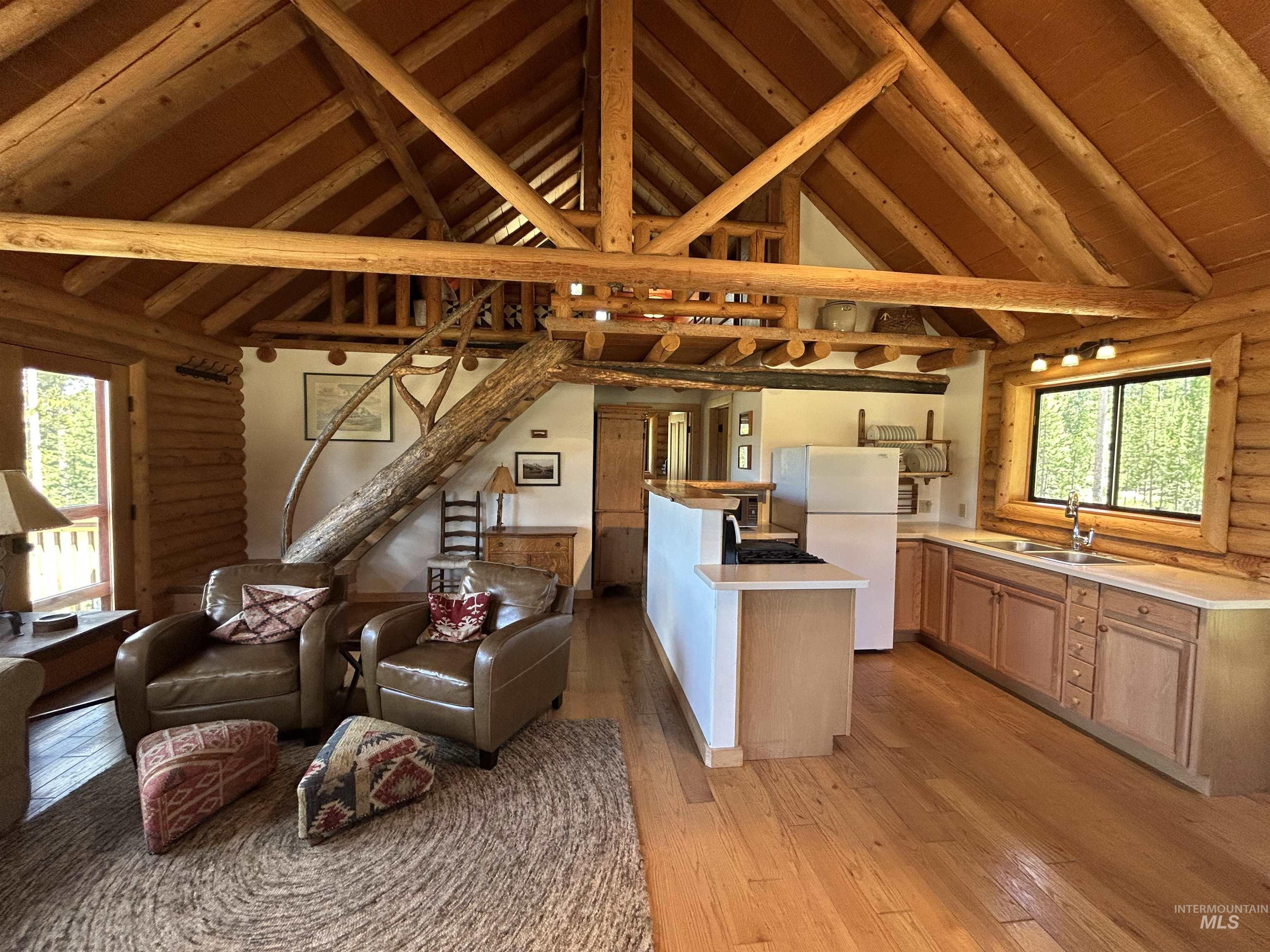 35 Sawtooth Way Stanley, ID 83278 - Photo 13 of 36 Open-concept living space featuring exposed log beam construction, vaulted ceilings, and wood-finish flooring