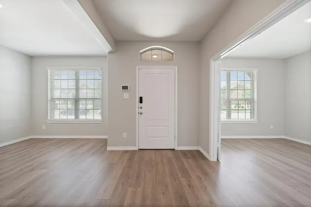 a view of an empty room with wooden floor and window