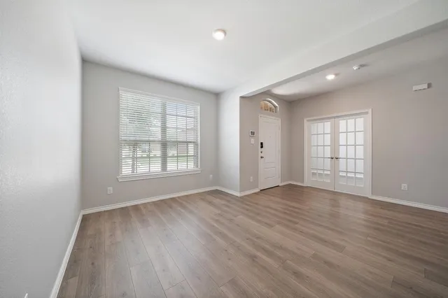 an empty room with wooden floor and windows