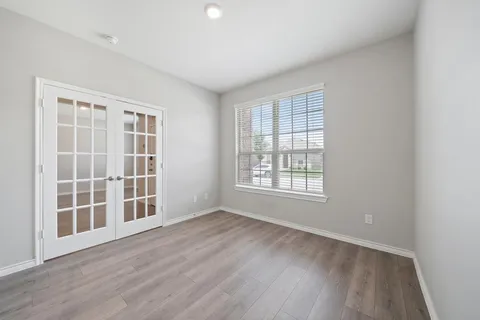 a view of an empty room with wooden floor fireplace and a window