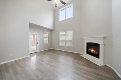 a view of an empty room with wooden floor fireplace and a window