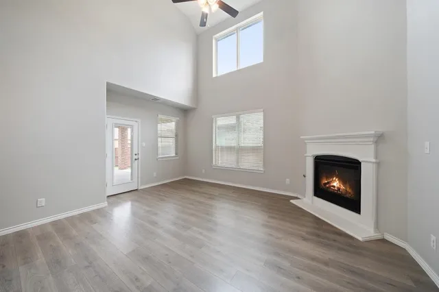 a view of an empty room with wooden floor fireplace and a window