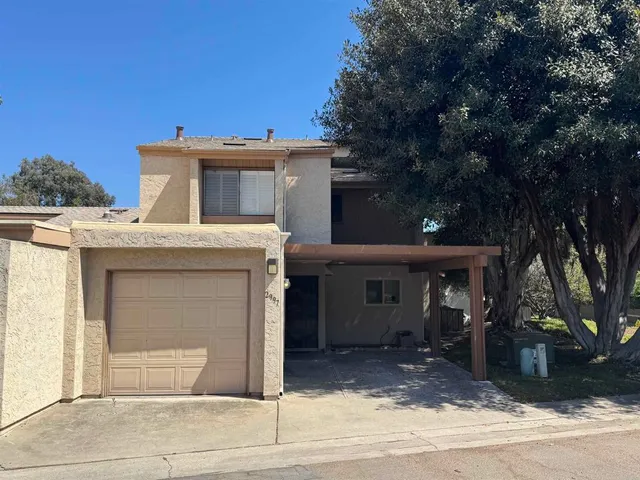 a view of a house with a garage and large tree