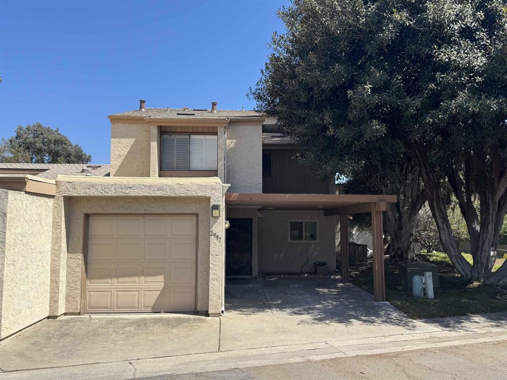 a view of a house with a garage and large tree