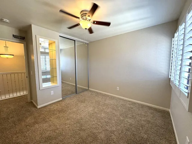 an empty room with windows and a chandelier fan