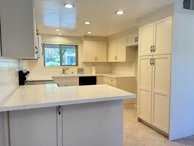 a kitchen with a sink a stove a refrigerator and white cabinets
