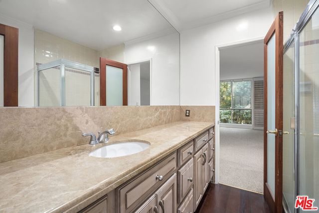 a bathroom with a granite countertop sink a mirror and a shower