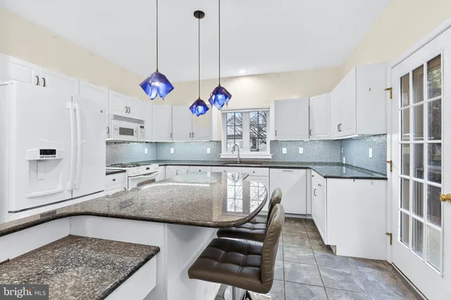 a kitchen with stainless steel appliances granite countertop a sink a stove and white cabinets