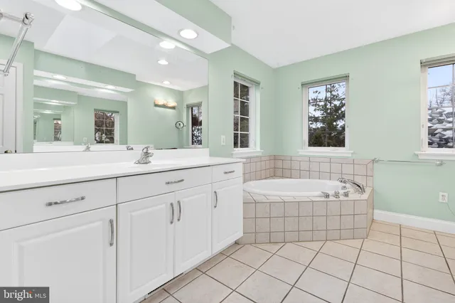 a spacious bathroom with a double vanity sink mirror and bathtub