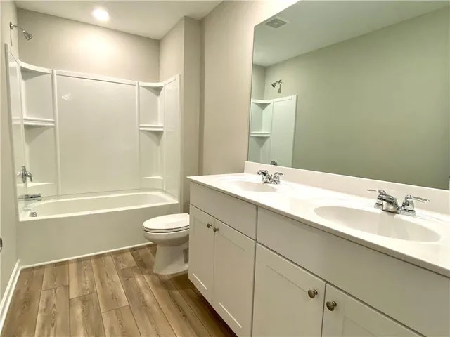 a bathroom with a bathtub shower sink vanity and toilet