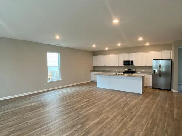 a large kitchen with stainless steel appliances granite countertop a large counter top and a stove top oven with wooden floor