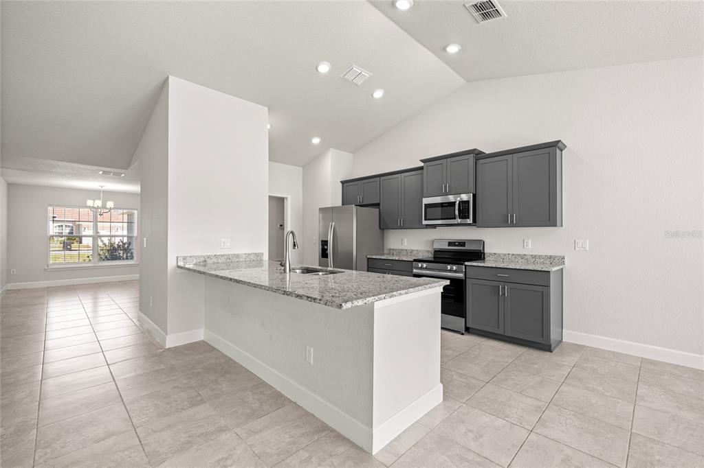 4984 Southwest 91st Place Ocala, FL 34476 - Photo 13 of 42 a large kitchen with a stove a sink and a refrigerator