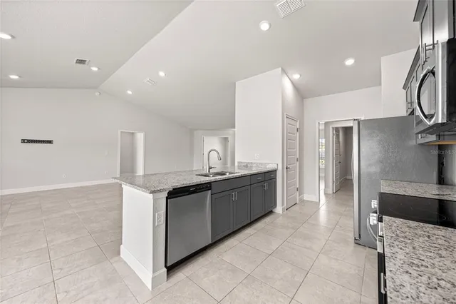 a kitchen with stainless steel appliances kitchen island granite countertop a refrigerator and a sink