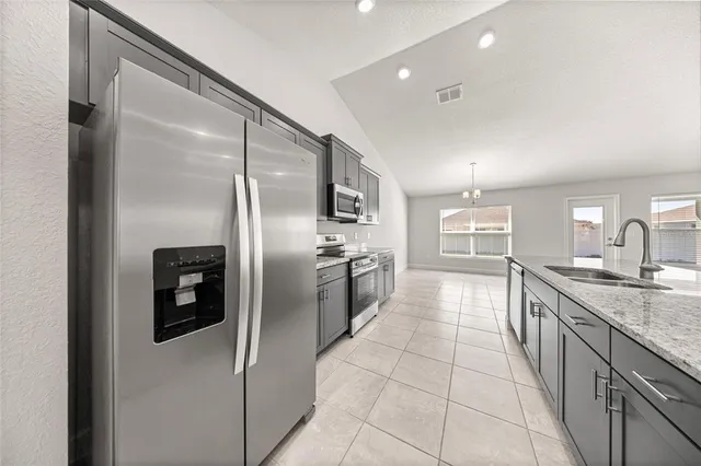 a large kitchen with stainless steel appliances granite countertop a refrigerator and a sink