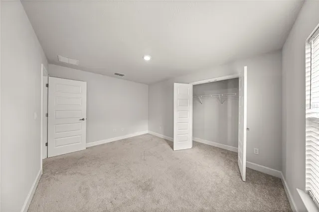 an empty room with window in back and closet area