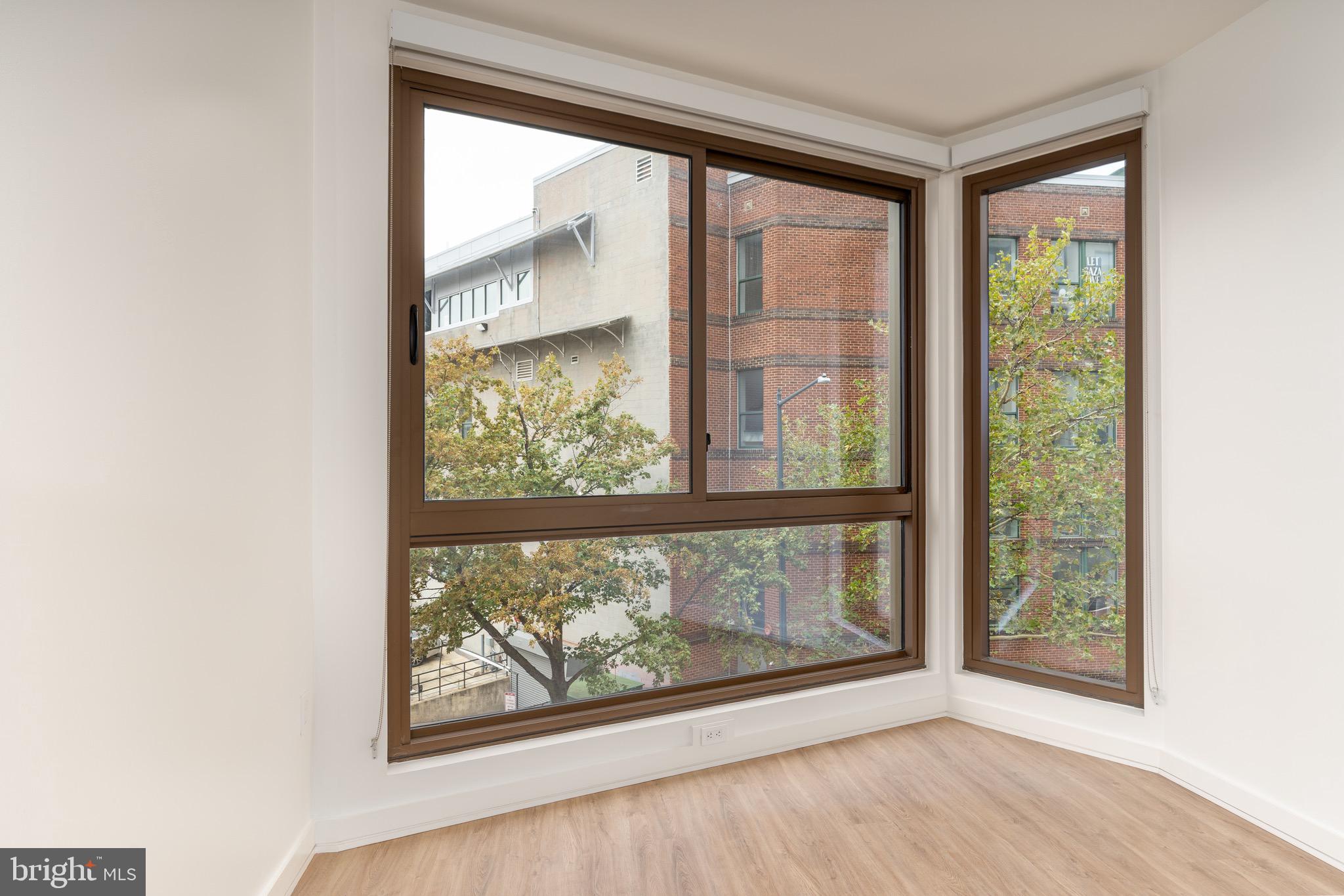 1630 Columbia Road Northwest, Unit 307 Washington, DC 20009 - Photo 4 of 21 an empty room with wooden floor and doors