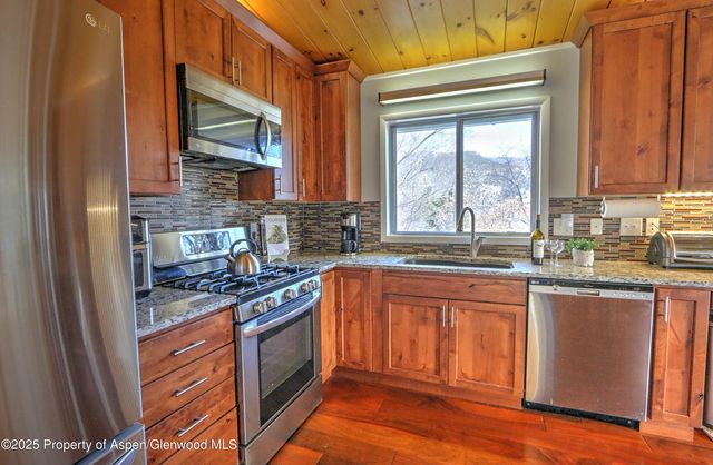 a kitchen with stainless steel appliances granite countertop a stove a sink and a microwave
