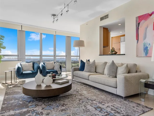 a living room with couches and a dining table with kitchen view