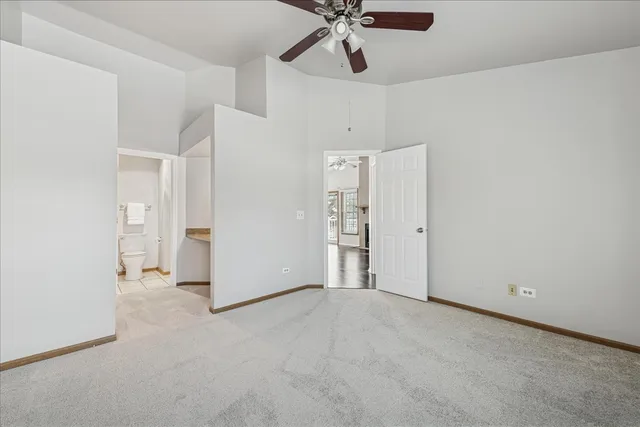 an empty room with a ceiling fan and hallway