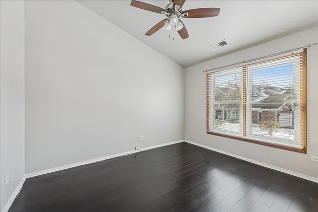an empty room with wooden floor fan and windows