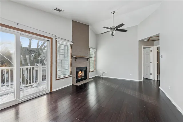 an empty room with wooden floor a ceiling fan and a fireplace