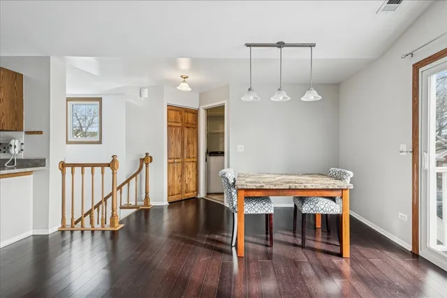 a dining room with wooden floor a chandelier a wooden table and chairs