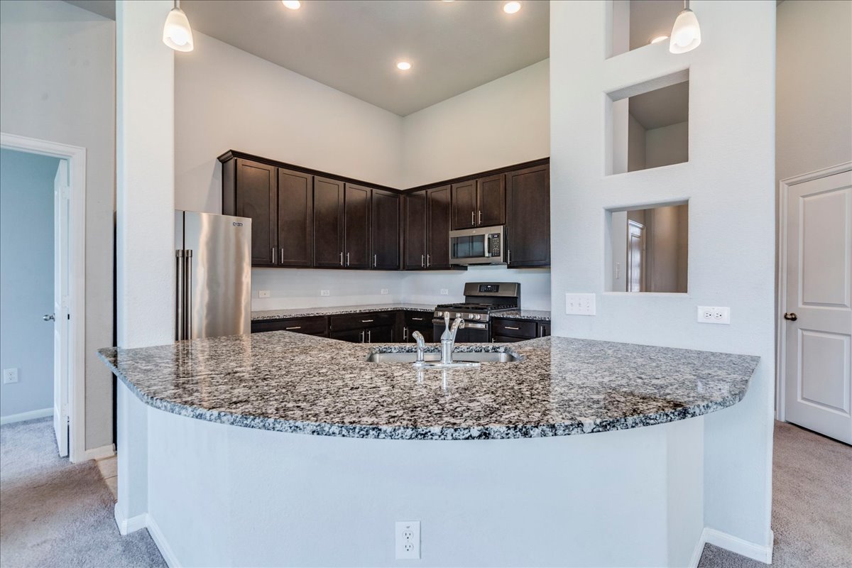 275 Cherrystone Loop Buda, TX 78610 - Photo 8 of 33 Large kitchen featuring granite countertops, espresso cabinets, stainless appliances and tons of counter and cabinet space.